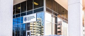 Glass building exterior with a sign for U.S. Citizenship and Immigration Services near the entrance, supported by Grand Prairie K-1 fiancé visa attorneys and Dallas citizenship and naturalization lawyers.
