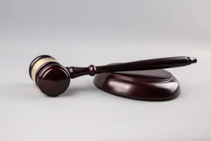 A wooden gavel rests on its matching sound block against a plain light gray background, symbolizing the work of Dallas citizenship and naturalization lawyers.