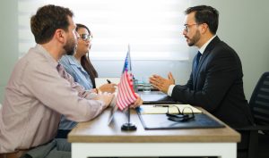 Three people are having a formal meeting on Adjustment of status Houston of her spouse.