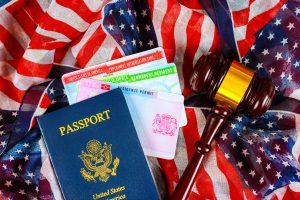 A U.S. passport, residence permits, and a judge’s gavel are displayed on an American flag-themed cloth, symbolizing the journey navigated with a Houston immigration lawyer.